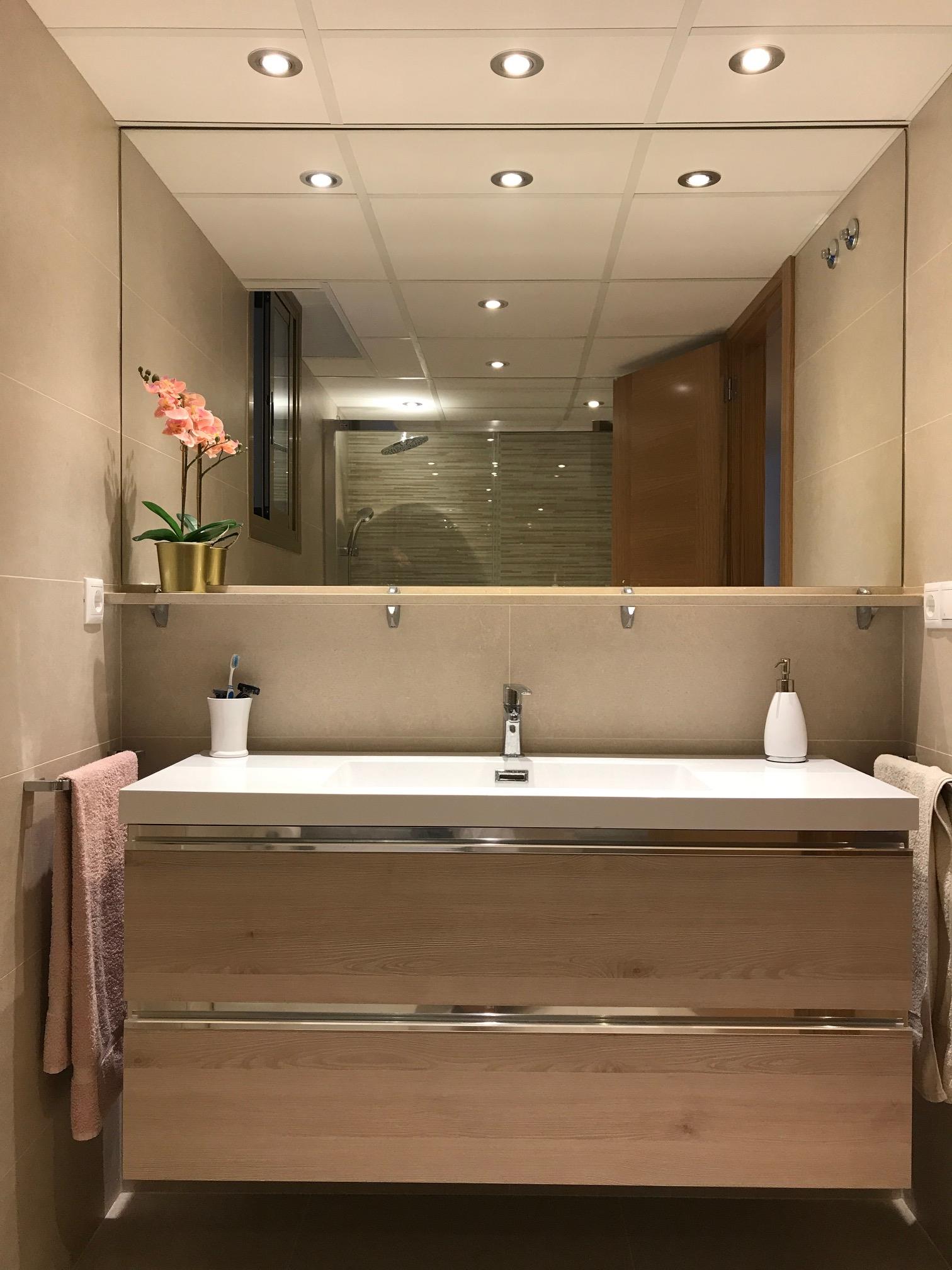 Baño integral reformado con iluminación cuidada en Alicante